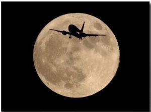 An Airliner is Silhouetted against a Full Moon